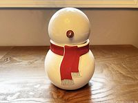 Front view of ceramic snowman cookie jar showing red scarf and lid seam