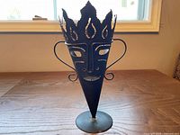 Front view of sheet metal tribal mask candle holder on pedestal base
