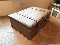 Closed suitcase angled view showing textured faux leather and stitched panels