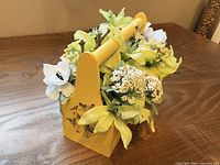 Front view of yellow wooden tote showing chalkboard tag and floral contents