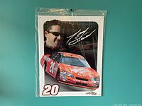 Front view of sealed Tony Stewart #20 metal sign hung on teal wall