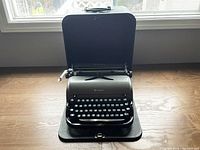 Typewriter seated on base with case lid upright