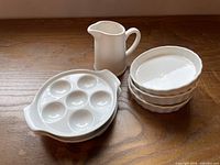 Group shot showing two escargot plates, three tart dishes, one creamer pitcher