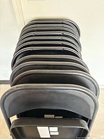 Stack of 12 black metal folding chairs folded flat