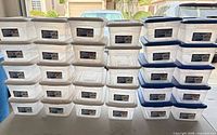 Front view of stacked clear bins with white and blue lids