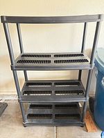 Full front view of black plastic 4-tier shelving unit
