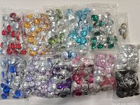 Bags of assorted colored faceted acrylic gems laid out flat