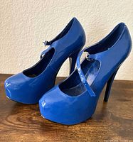 Side view of both blue patent Bordello pumps showing platform and stiletto heels