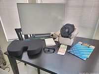 Overall lot showing whiteboard, seat cushion, desktop fan in box, clipboards, labels, glasses