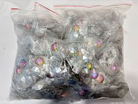 Sealed clear plastic bag containing multiple smaller bags of iridescent faceted craft gems