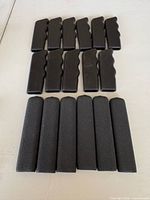 Grouped view showing 17 flat grip handles; top rows vinyl with finger contours, bottom row foam grips