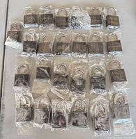 25 individually wrapped black padlocks in rows with bag of loose keys
