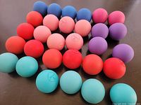 Thirty multicolored rubber balls spread on dark surface