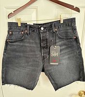 Front view of washed black Levi's 501 '93 cutoff shorts with tag attached