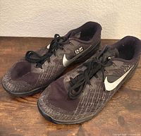 Pair of black Nike Metcon 3 sneakers side view on wooden surface