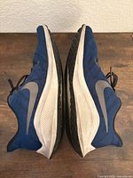 Side profile of both shoes showing blue uppers and grey Swoosh