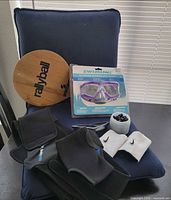 All items grouped on seat: paddle, packaged mask, jar of cord stops, sweatbands, braces