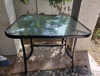Full view of square glass patio table with metal frame