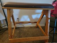 Side view of wooden bench showing A-frame legs and upholstered seat