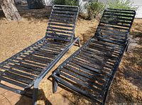 Two matching metal slat chaise lounges side by side