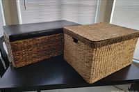 Both wicker bins on table showing size and style differences