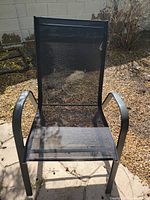Front view of single black patio chair showing metal frame and mesh seat/back