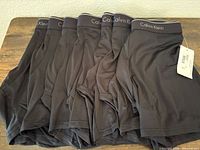 Seven black Calvin Klein boxer briefs stacked