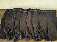 Eight black boxer briefs laid out showing waistband text