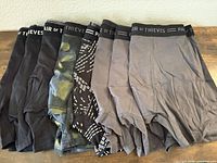 All eight boxer briefs folded showing waistband branding and colour variety