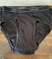 Stack of nine black Hanes briefs showing front style and waistband