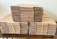 Three bundled stacks of flattened brown corrugated cardboard boxes