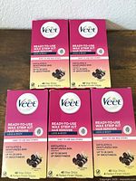 Front view of five Veet wax strip kit boxes