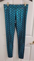 Front view metallic teal mermaid scale leggings hanging
