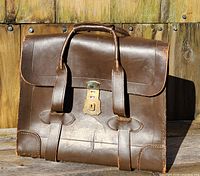 Front view of brown leather flight briefcase with brass lock and dual handles