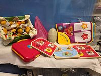 Lot overview with basket of capsules, puzzles, cloth book, egg, sound module