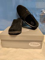 Oblique view of both shoes resting on original box