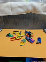 Group of eight Kinder Surprise toy boats on yellow background