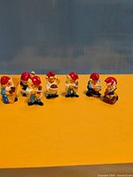 Seven dwarf figurines lined up on yellow surface