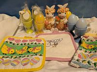 Group shot of all Easter items including pot holders, towel, bunny figurines, dove candle holder, egg candles