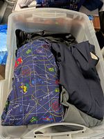 Overview of tote showing blue novelty-print garment, black jacket, navy jacket
