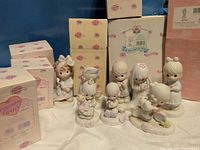 Seven Precious Moments figurines front, six branded boxes rear