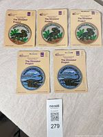 Group view of all five sealed dinosaur patches on cards