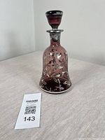 Front view of purple glass decanter with silver overlay and stopper