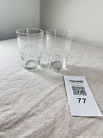 Two clear cut crystal tumblers on table with lot tag
