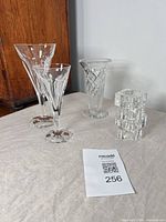 All items grouped on tabletop: two wine glasses, four napkin rings stacked, single vase visible