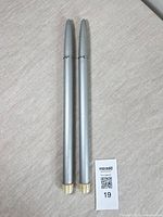 Pair of silver-tone candle lighters with gold-tone bases displayed side by side on tabletop