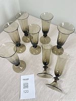 Eight smoked glass champagne flutes grouped on table