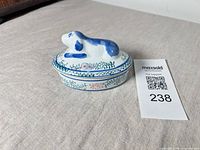 Side view of oval ceramic box with dog lid