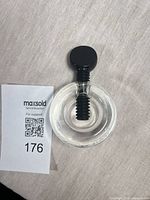 Top view of clear circular nutcracker showing black screw and knob