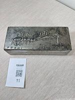 Top view showing embossed ostrich procession and landscape on lid